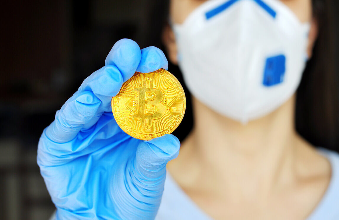 woman holding a bitcoin in coronavirus gear