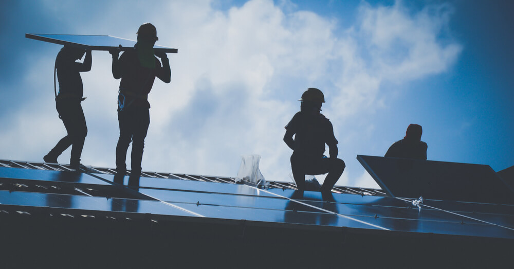 Image of a group of people helping each other build solar panels