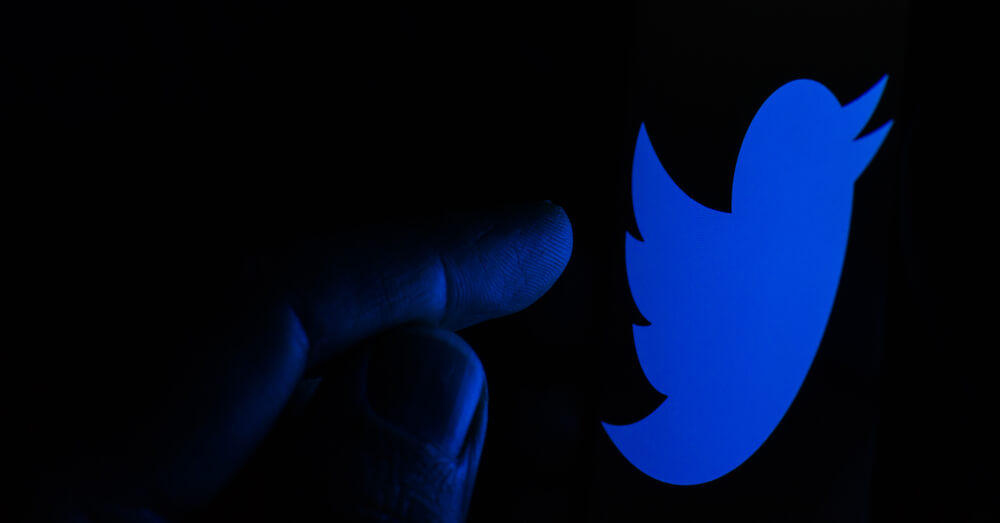 Image of Twitter’s logo with finger touching it