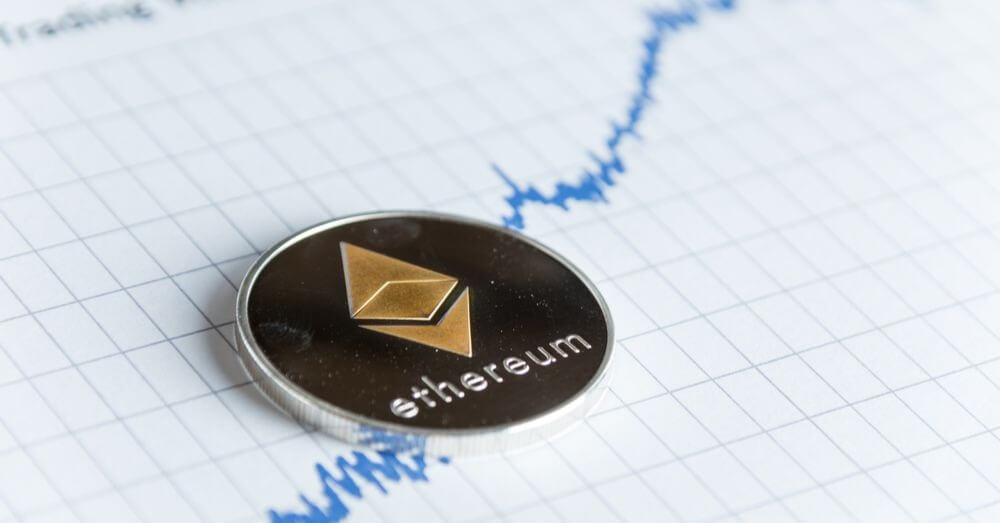 An image of a Ethereum coin on top of a paper showing a rising trend