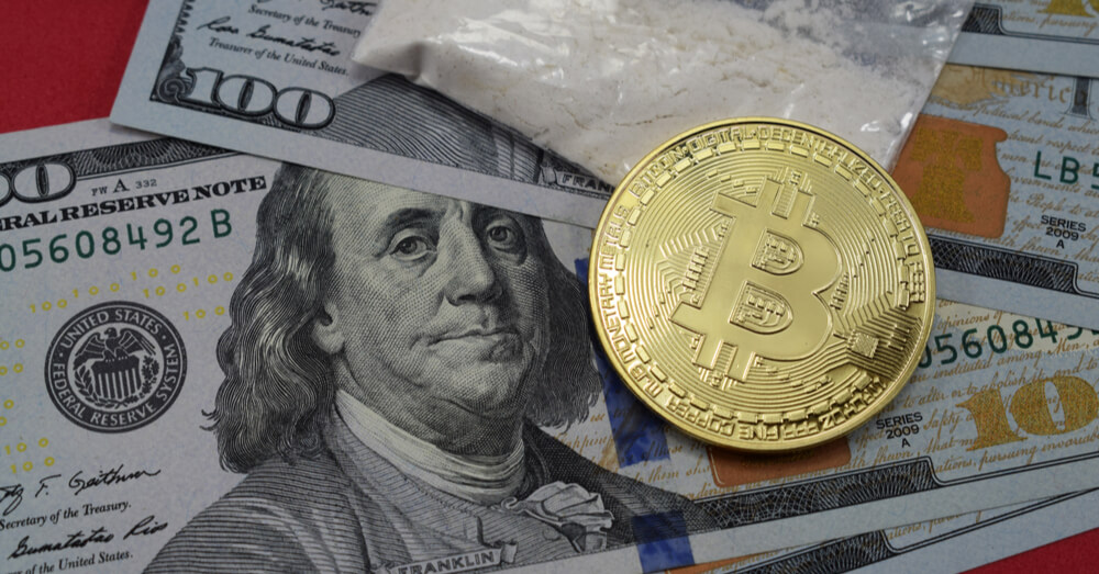 An image of US dollars, drugs and a Bitcoin on a red surface