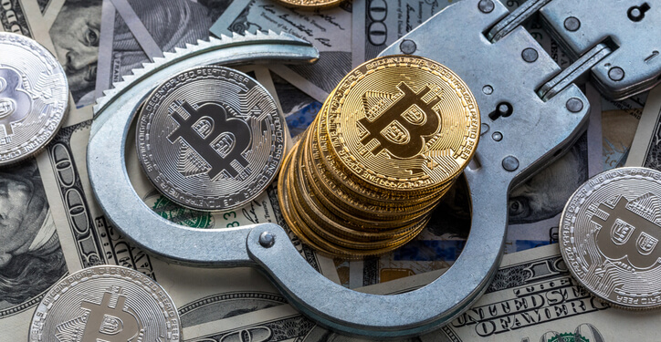 Stack of bitcoins and metal handcuffs on banknotes