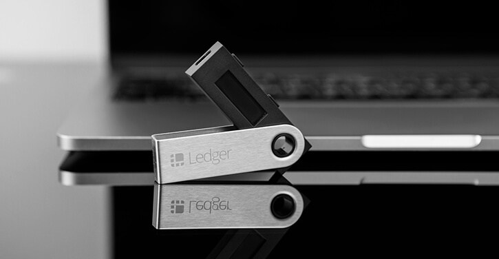 An image of a Ledger hardware wallet placed next to a laptop