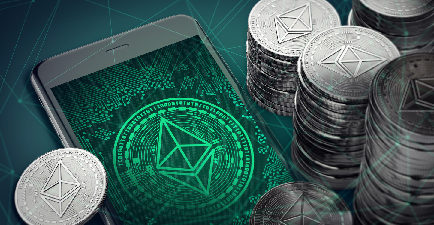 Smartphone with Ethereum symbol on-screen among piles of Ether