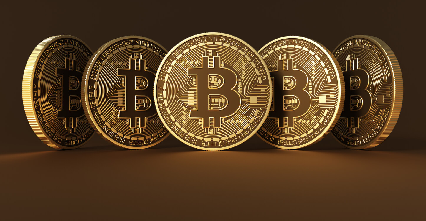 An image of five bitcoins on a brown background