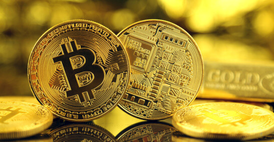 2 gold bitcoins standing on their sides, with more lying horizontally on a golden surface