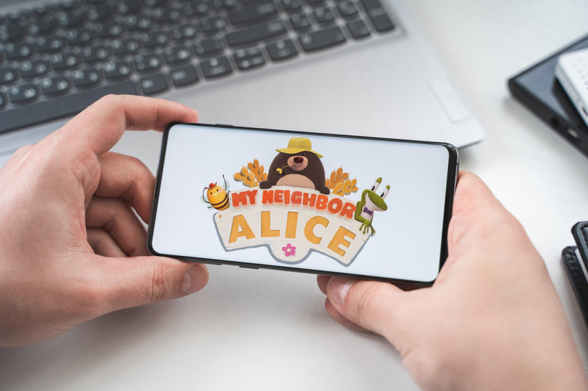 MyNeighborAlice (ALICE) logo on a mobile phone being held by 2 hands