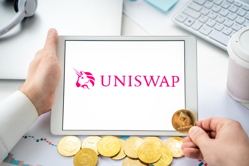Uniswap Logo on a tablet screen, with coins behind it