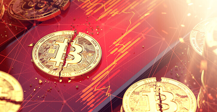 Een gebroken Bitcoin gesplitst in twee stukken met een rood gekleurde marktgrafiek