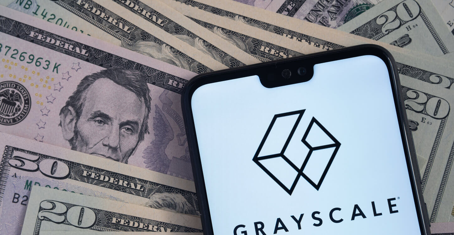 Het Grayscale logo op een smartphone, die bovenop dollarbiljetten ligt