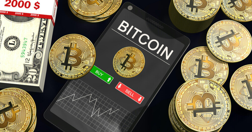 Smartphone met een Bitcoin grafiek op het scherm tussen stapels van Bitcoins