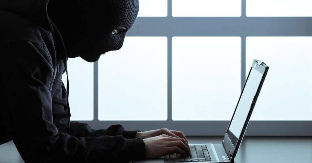 Een gemaskerde hacker achter een laptop