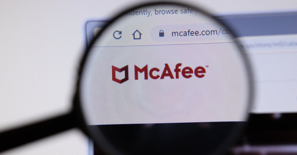 Foto van het logo van de McAfee website onder een vergrootglas