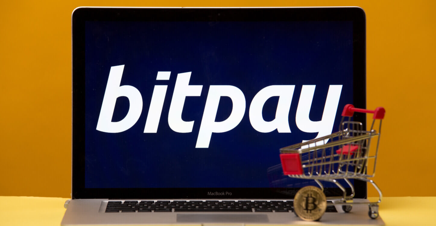 Foto van een mini-winkelwagentje en Bitcoin op een laptop met het BitPay logo