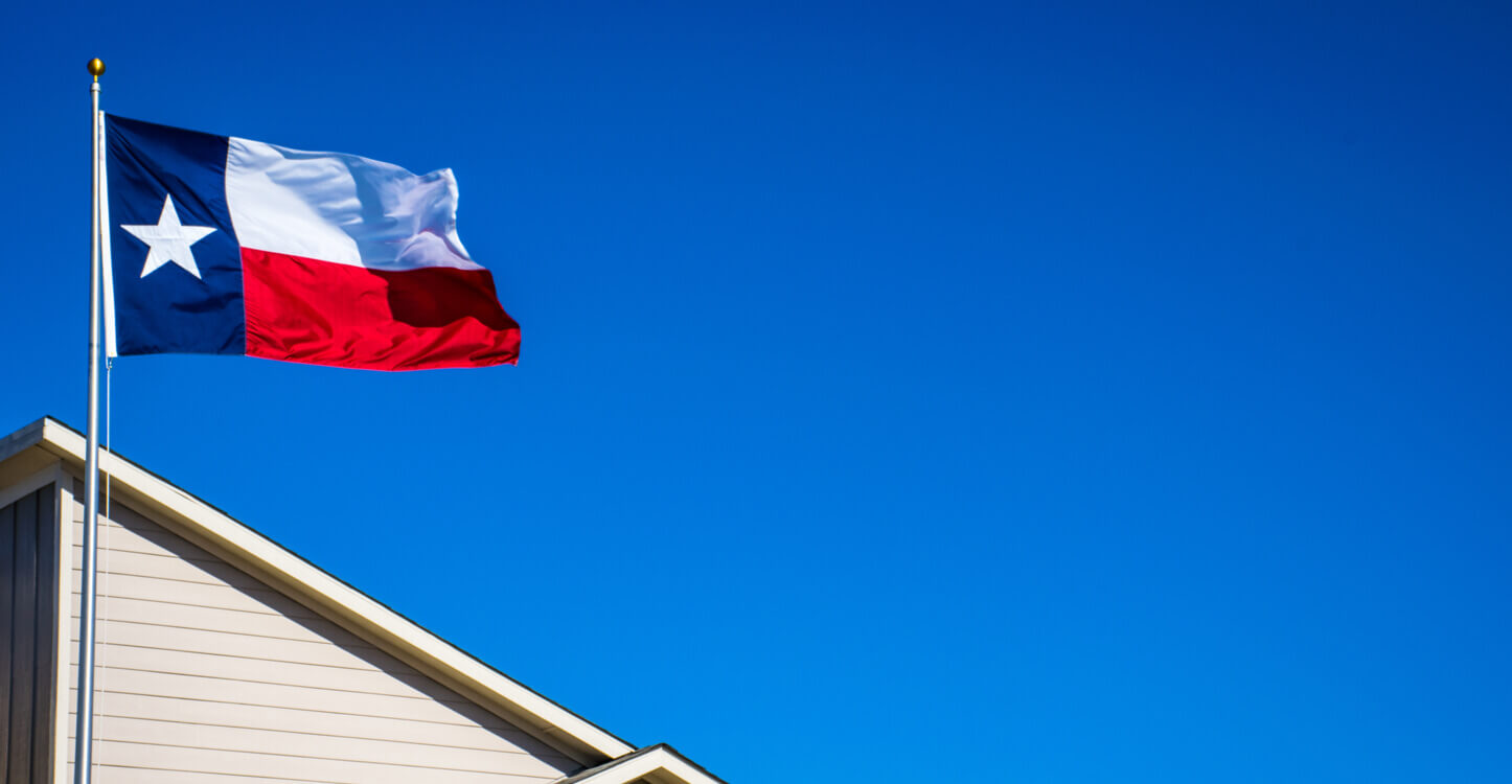 Foto van de vlag van Texas naast een huis