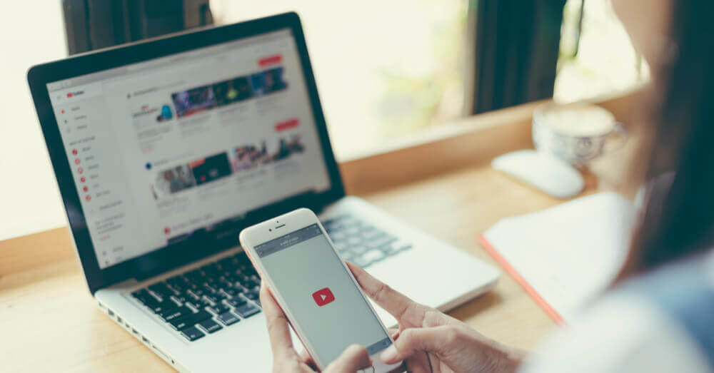 Foto van een vrouw die YouTube op haar laptop en telefoon gebruikt