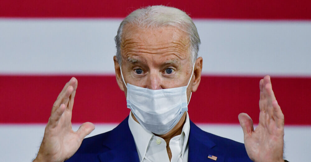 Foto van de verkozen president Joe Biden met een masker die een toespraak voor een Amerikaanse vlag houdt