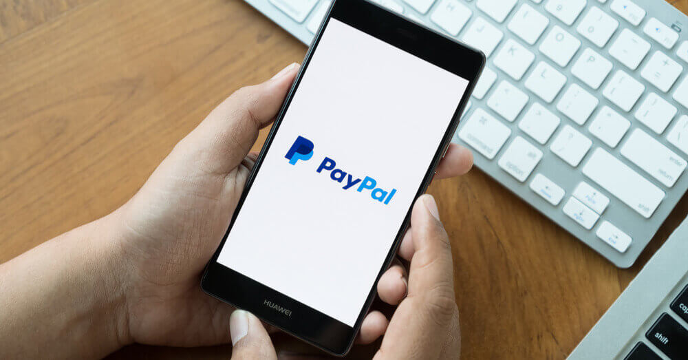 Foto van Paypal op een mobiele telefoon naast een toetsenbord