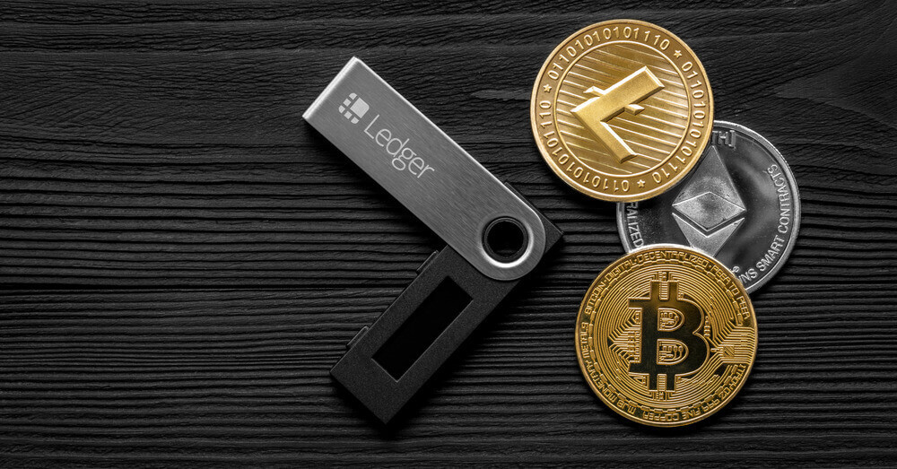 Portefeuille matériel Ledger avec trois pièces représentant des crypto-devises : Litecoin, Ethereum et Bitcoin