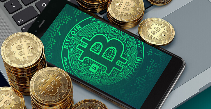 Smartphone avec le symbole BTC autour de piles de Bitcoin