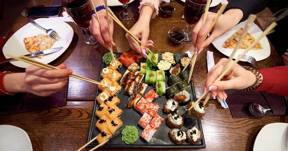 Des gens à une table qui prennent des sushis