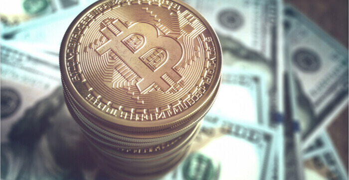 Coin Bitcoin en or sur un tas de billets de cent dollars