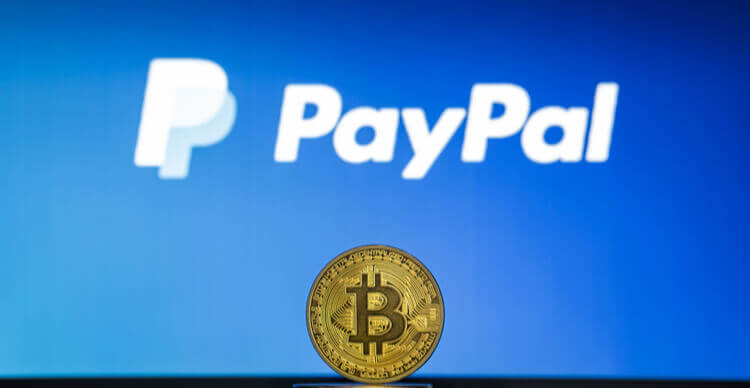 Bitcoin sur une pile de coins avec le logo PayPal sur un écran d'ordinateur portable