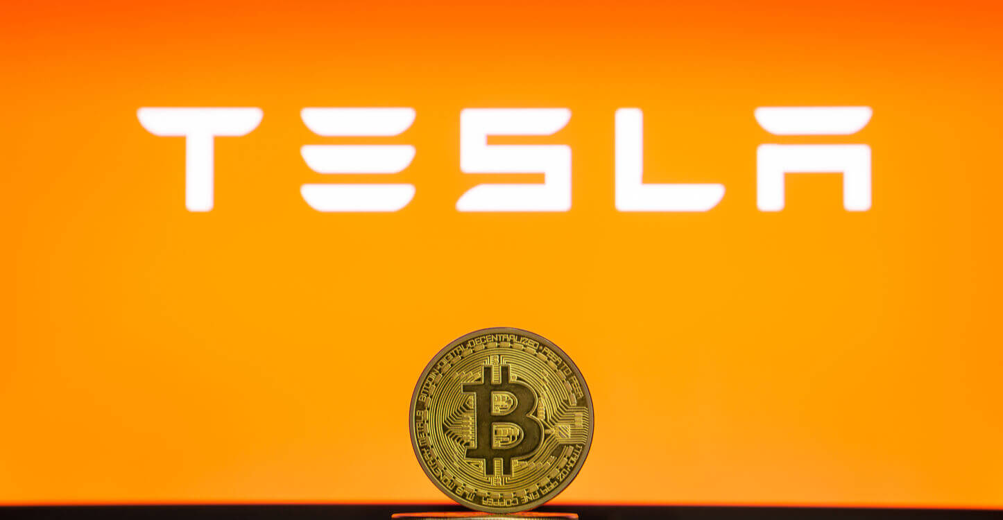 Bitcoin sur une pile de coins avec le logo Tesla sur l'écran d'un ordinateur portable