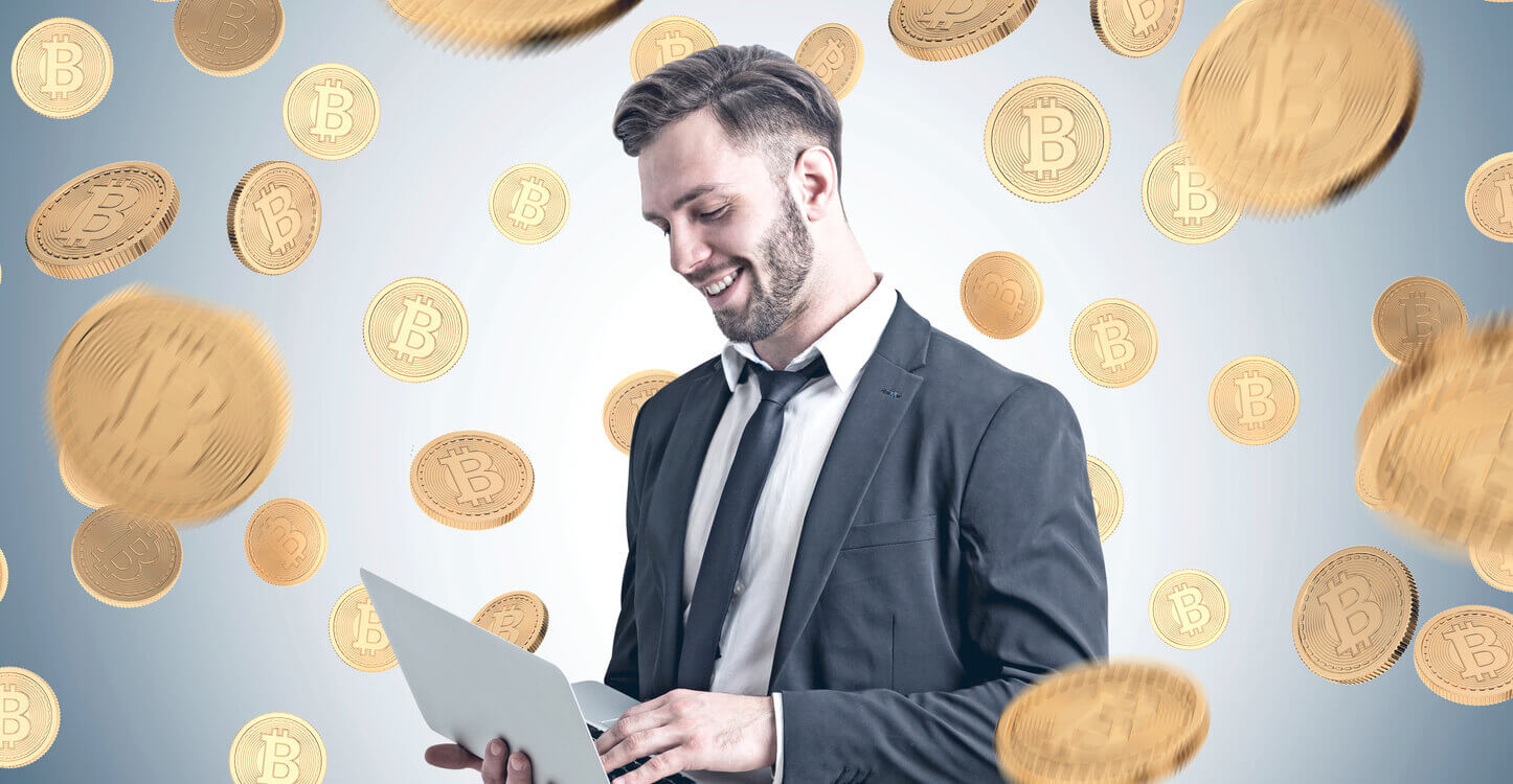 Un homme d'affaires tenant un ordinateur portable et se tenant sous une pluie de Bitcoin