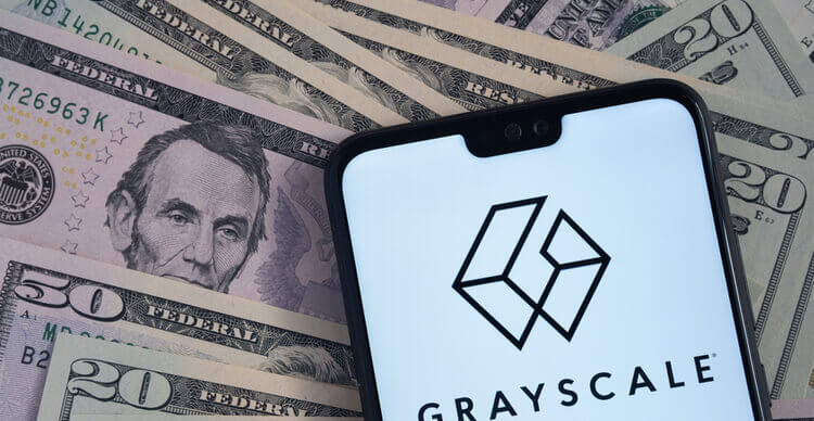 Logo de Grayscale vu sur l'écran d'un smartphone, placé sur des billets de banque