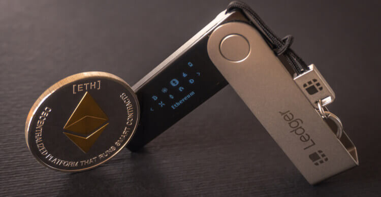 Image d'un hardware wallet Ledger à côté d'un jeton Ethereum.