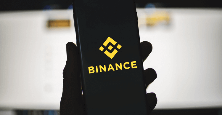 Une image d'une main tenant un téléphone affichant le logo de Binance