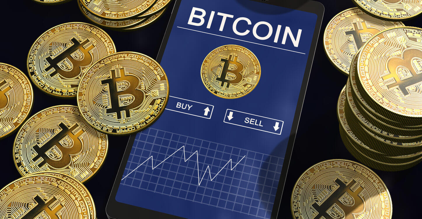 Graphique du cours du Bitcoin sur l'écran d’un smartphone entouré de Bitcoins doré