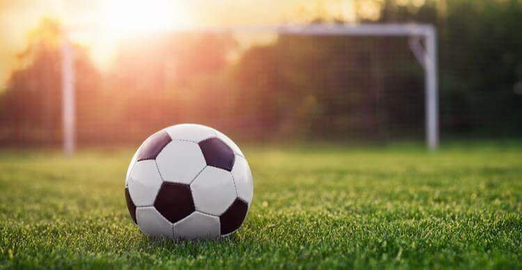 Image d'un ballon de football sur l'herbe près de poteaux de but.