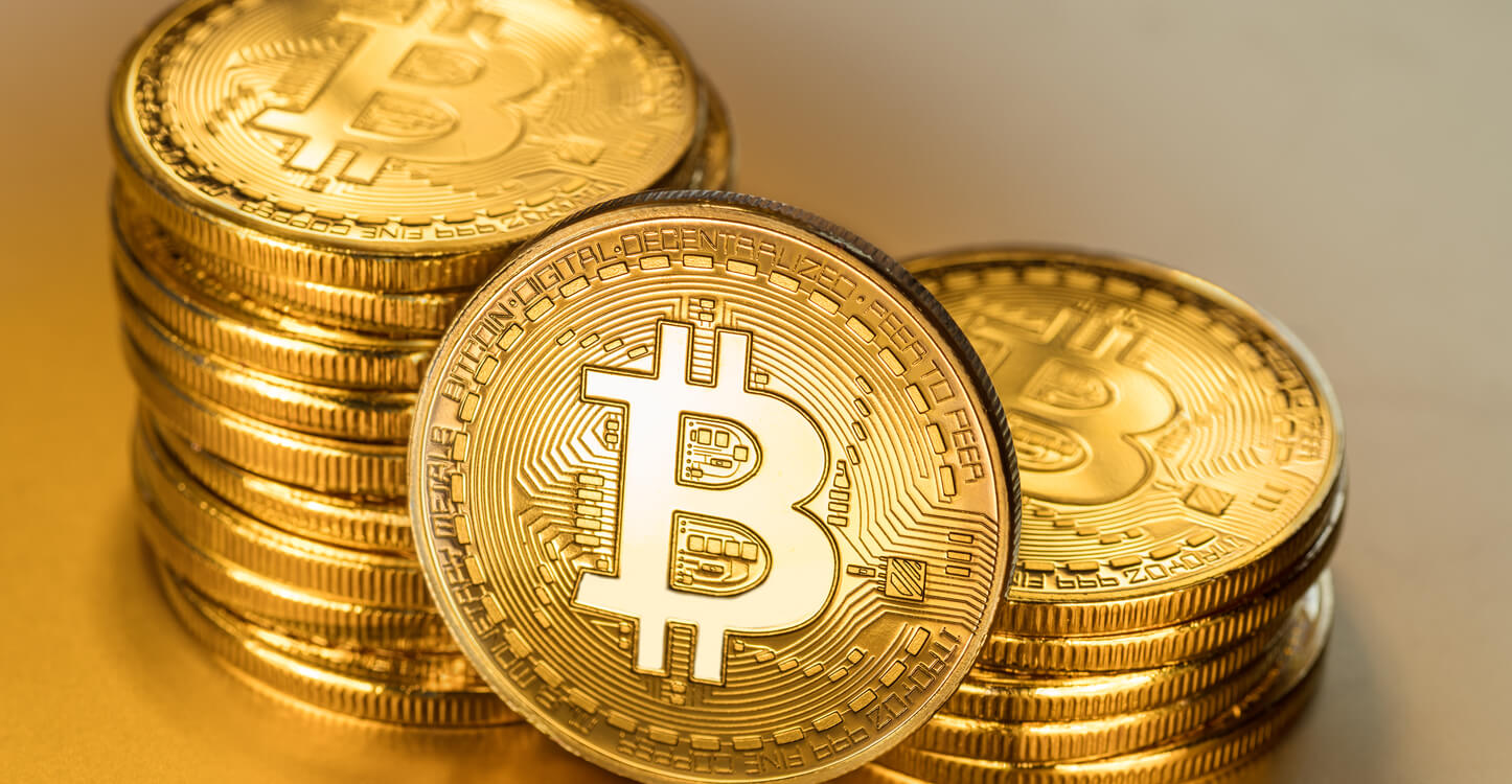 Physische Bitcoins vor goldenem Hintergrund