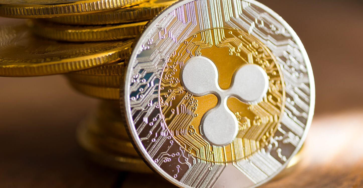 Ein Münz-Stapel und ein goldener XRP vor hölzernem Hintergrund