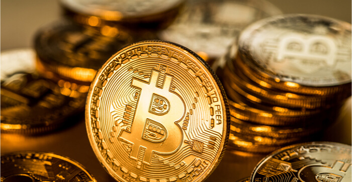 Glänzende physische Bitcoins auf goldenem Hintergrund