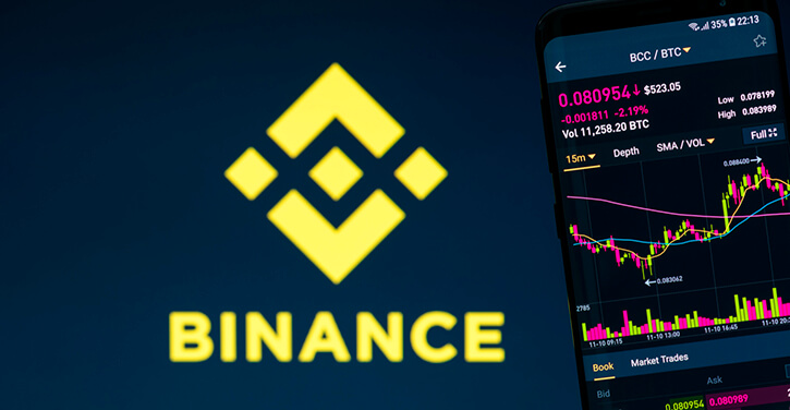 Ein Binance-Logo neben einem Smartphone mit einer BNB-Preistabelle