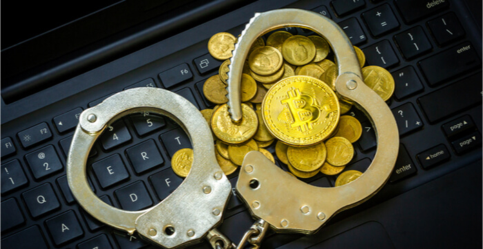 Goldene Bitcoins mit Handschellen auf einer Computertastatur