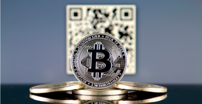 Bild von Bitcoins vor einem unscharfen QR-Code