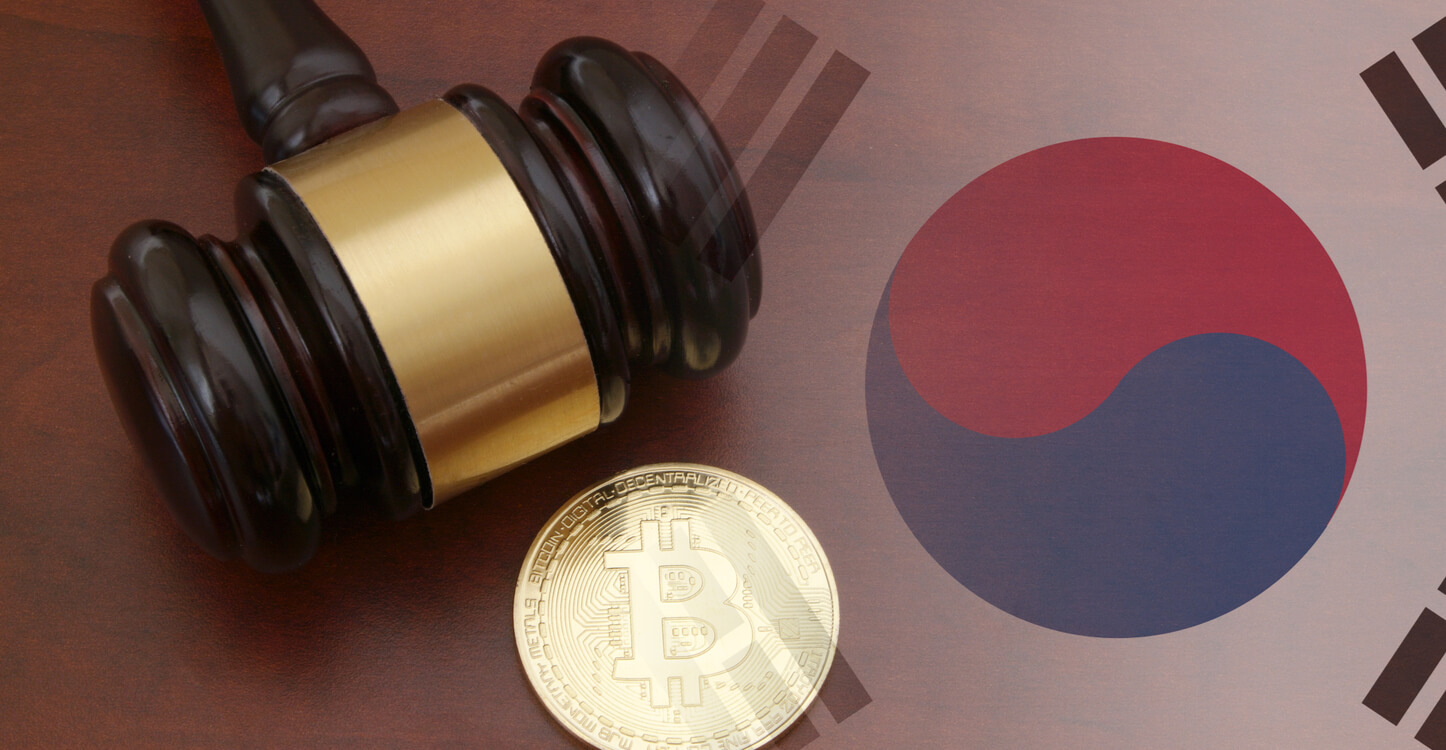 Ein Bild von einem Hammer und einem Bitcoin auf einem Tisch mit der südkoreanischen Flagge