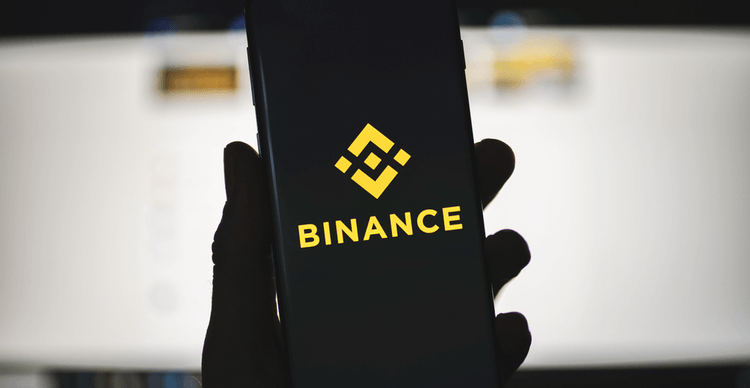 Ein Bild einer Hand, die ein Telefon hält, das das Binance-Logo zeigt