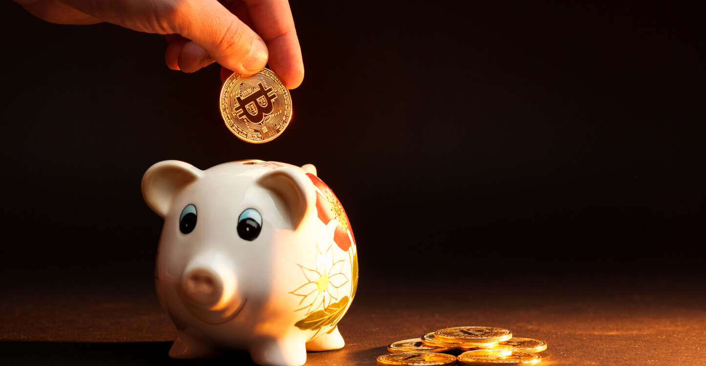 Image of a bitcoin being deposited into a piggy bank